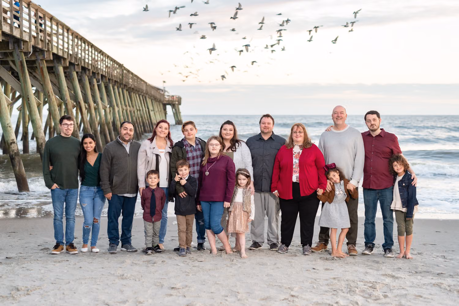 Large family lined up on the beach beside the pier as a flock of seagulls flies overhead at Myrtle Beach State Park