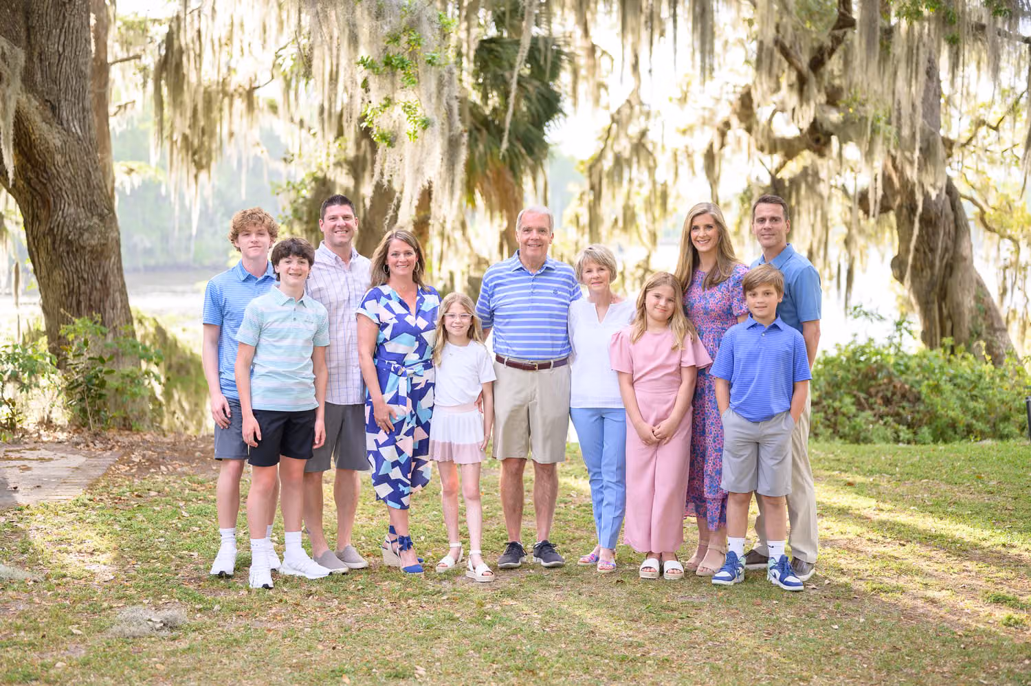 Large family standing on the lawn under oaks with Spanish moss in evening light at Wachesaw Plantation