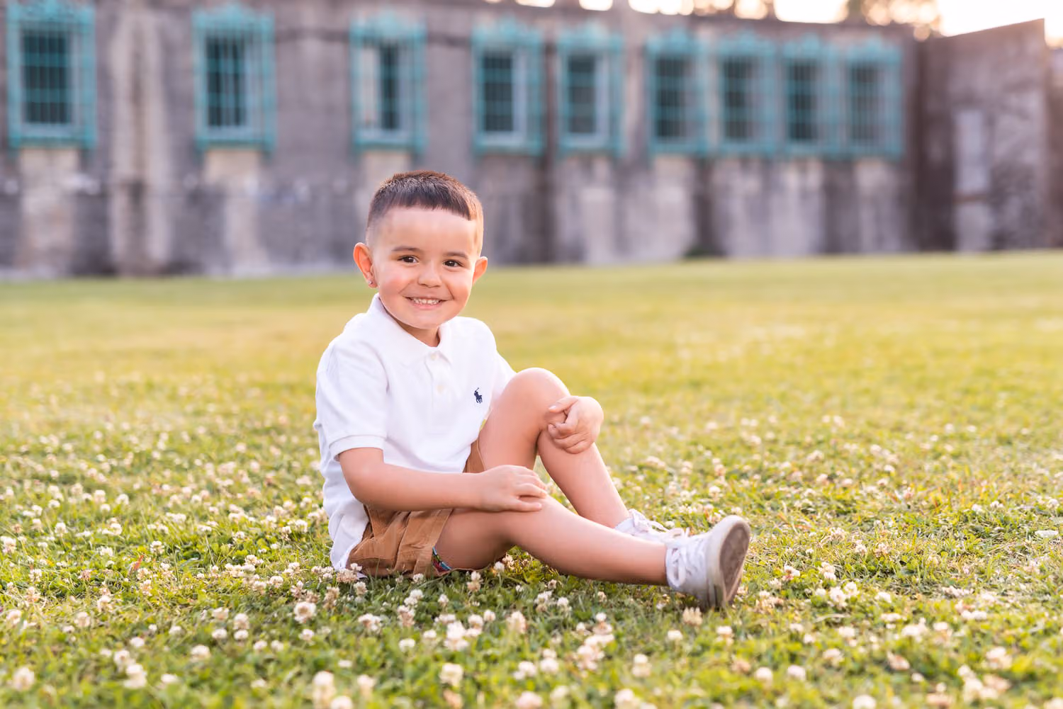 Little boy in a white shirt sitting in the clover in front of Atalaya Castle at Huntington Beach State Park