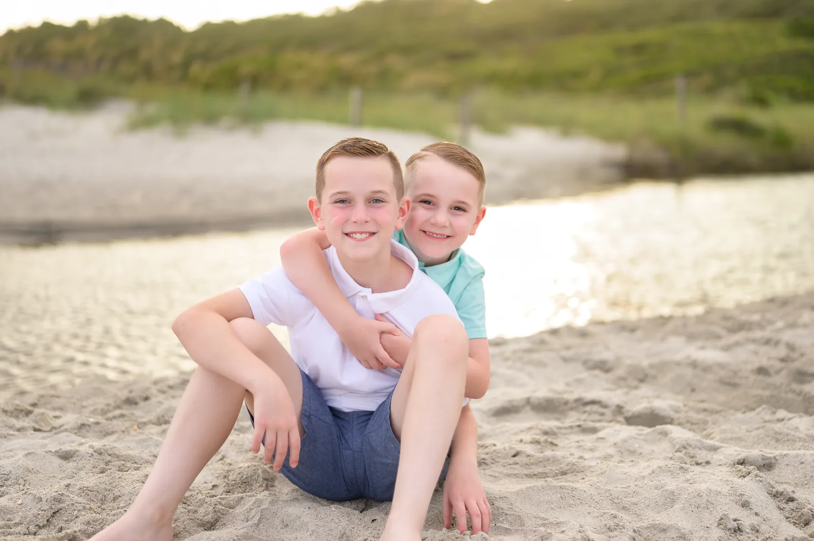 Happy brothers sitting by the sunset reflecting on the water - Myrtle Beach State Park