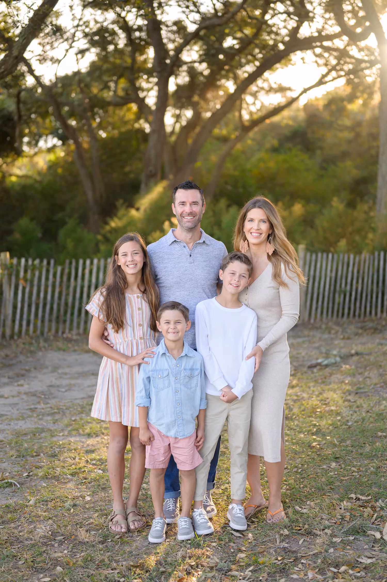 Family of five standing on a sandy path under old oaks with the sun setting behind them at Myrtle Beach State Park