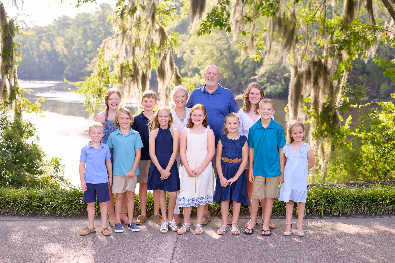 Grandparents standing behind a row of grandkids under oaks with Spanish moss by the river at the Conway Riverwalk