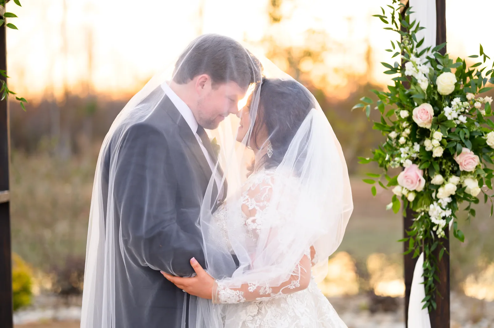 Veil over bride and groom with sunset - The Venue at White Oaks Farm