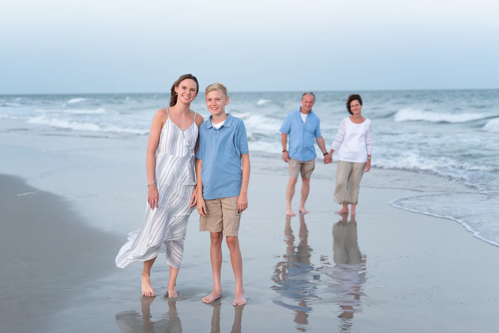 Brother and sister with parents holding hands in the background - Huntington Beach State Park