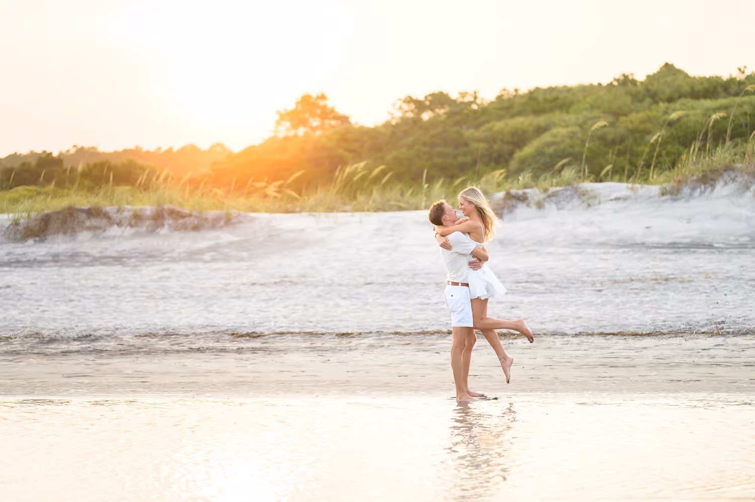 Couple embracing in the water at sunset at Huntington Beach State Park.