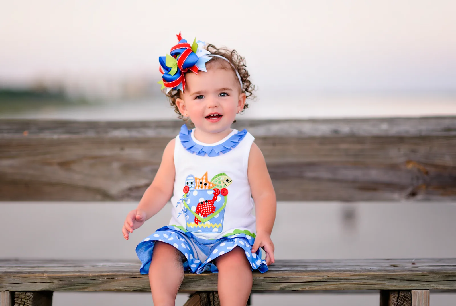 Little girl with colorful bow sitting on the pier - Myrtle Beach State Park
