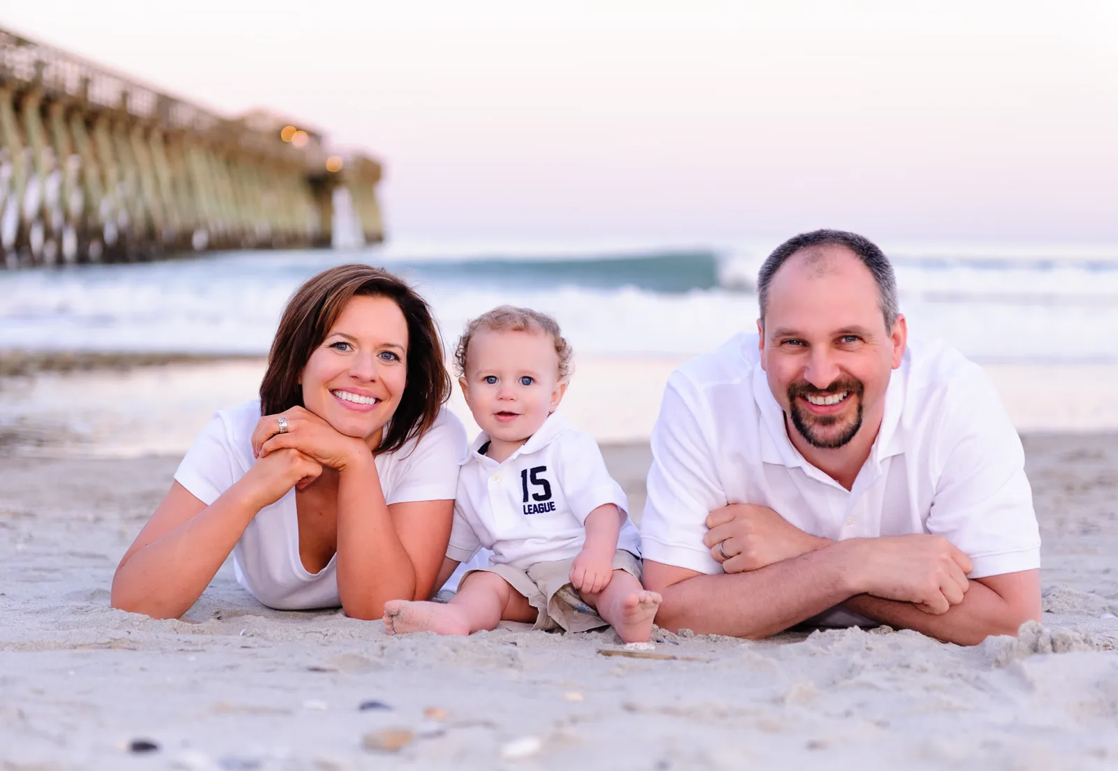 Nice family with little boy laying in the sand together - Myrtle Beach State Park Pier