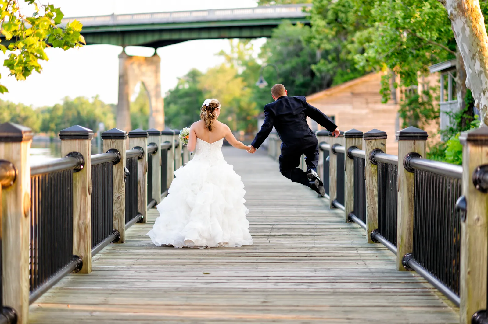 Happy groom leaping into the air and clapping feet - Conway River Walk