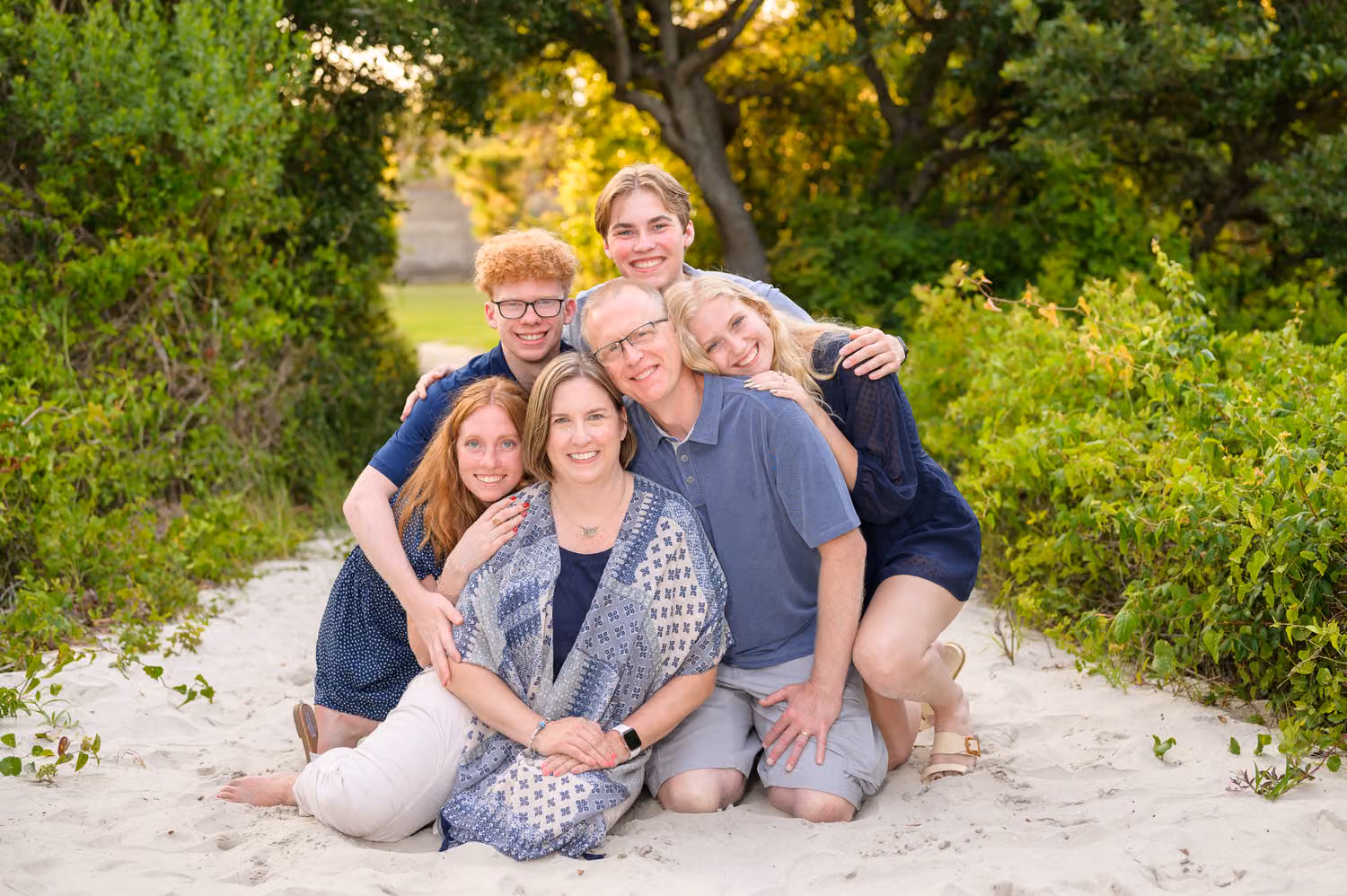 Grown kids wrapping their parents in a big hug as they sit on the beach path at Huntington Beach State Park