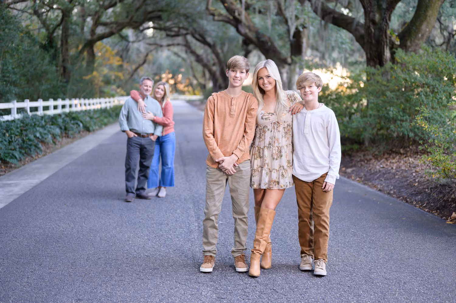Three kids standing on the oak avenue in front while mom and dad hug in the distance at Caledonia Golf & Fish Club