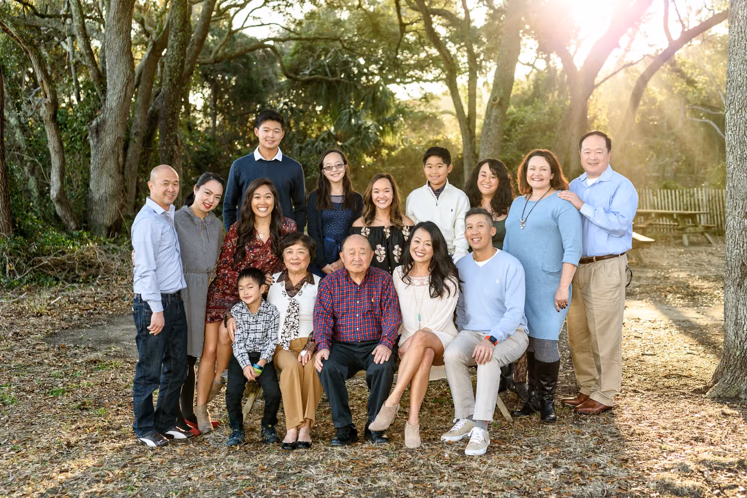 Large extended family gathered around a picnic table under oak trees at Myrtle Beach State Park