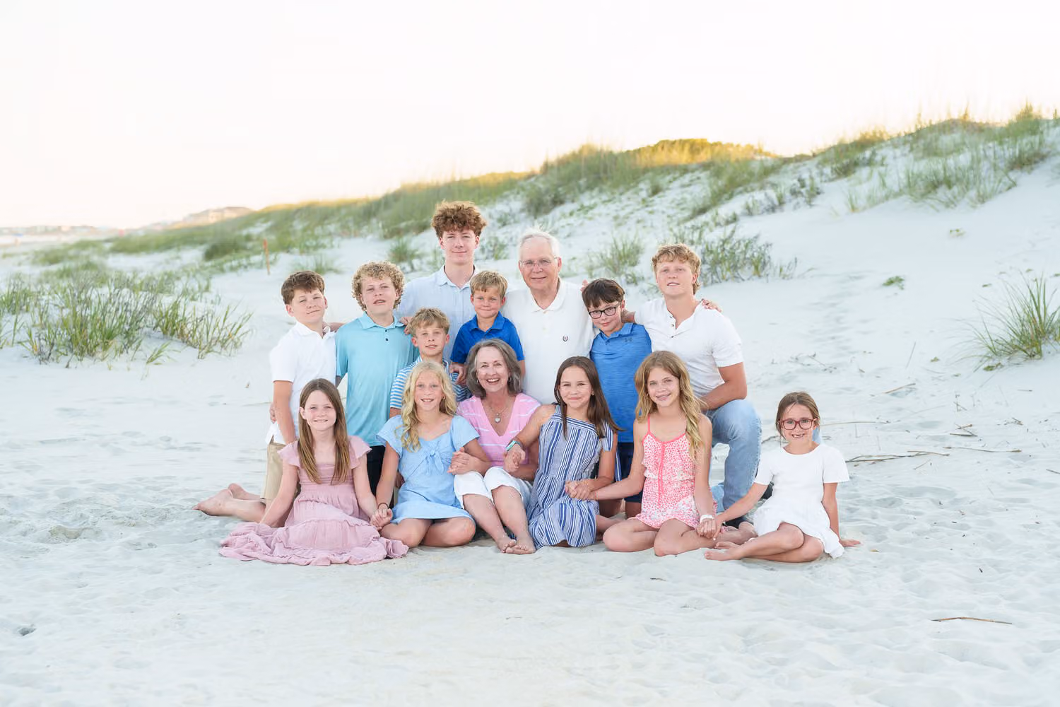 Grandparents surrounded by their grandkids sitting together in the sand dunes at Huntington Beach State Park