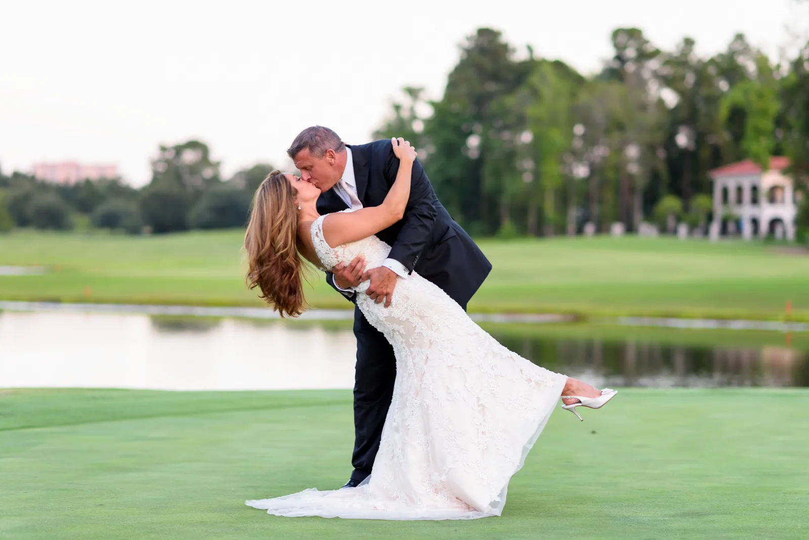 Groom dipping back bride for a kiss on the golf course - Members Club at Grande Dunes