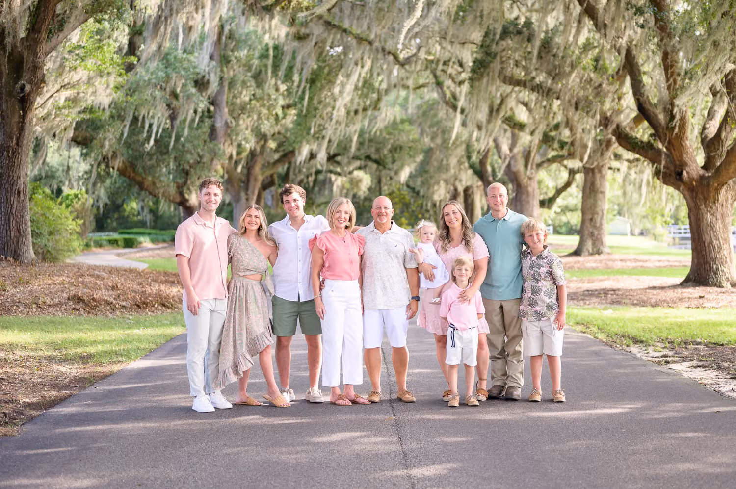 Family standing together on a paved road under oaks draped in Spanish moss at Caledonia Golf & Fish Club