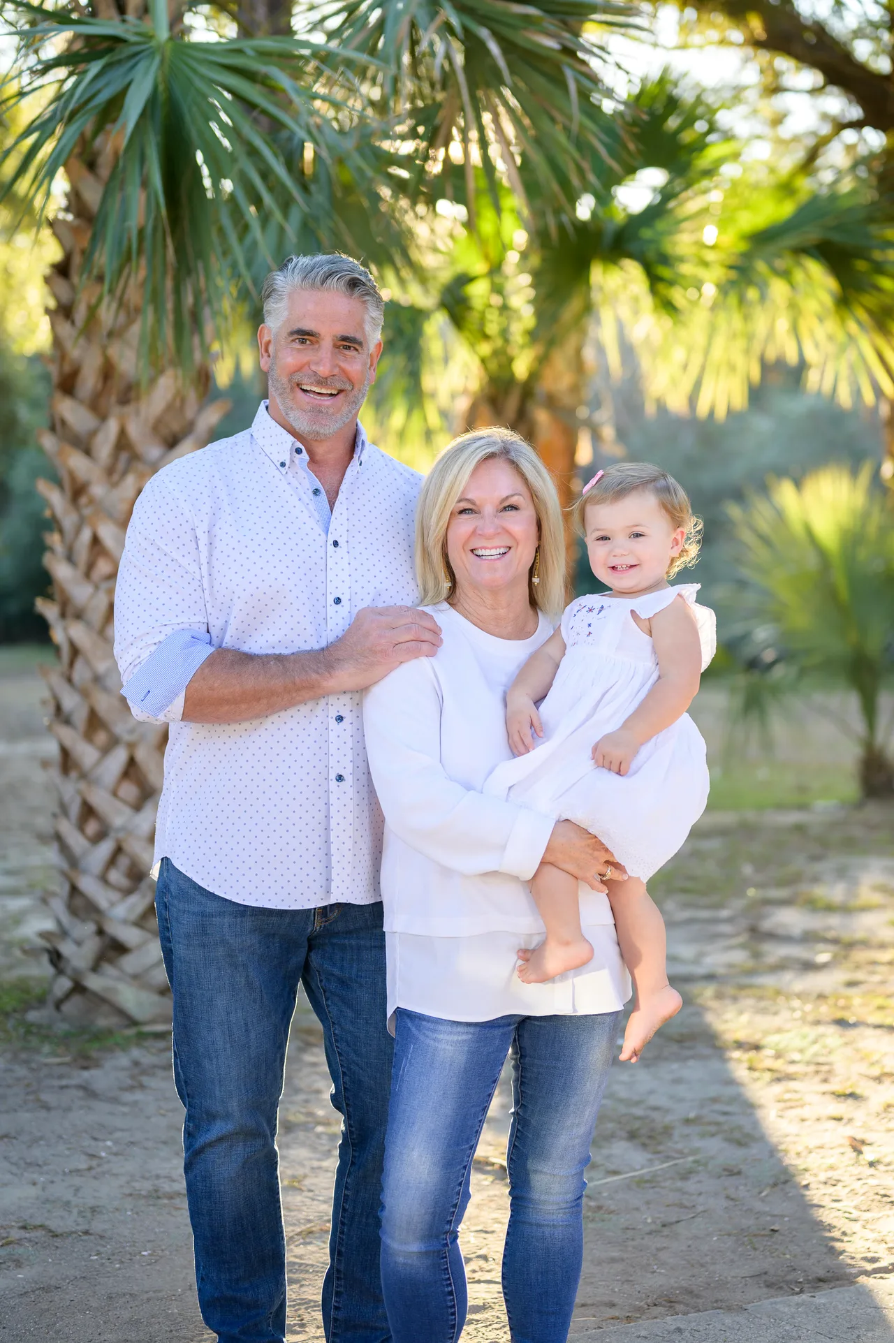 Grandparents with baby girl standing in front of the Palm Trees - Huntington Beach State Park