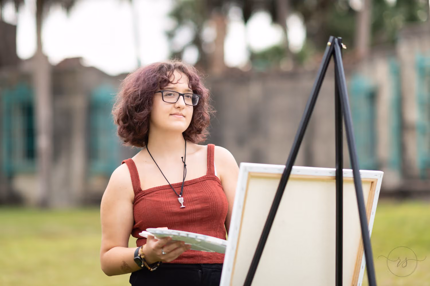 Senior painting on a canvas at an easel on the lawn in front of the castle at Huntington Beach State Park