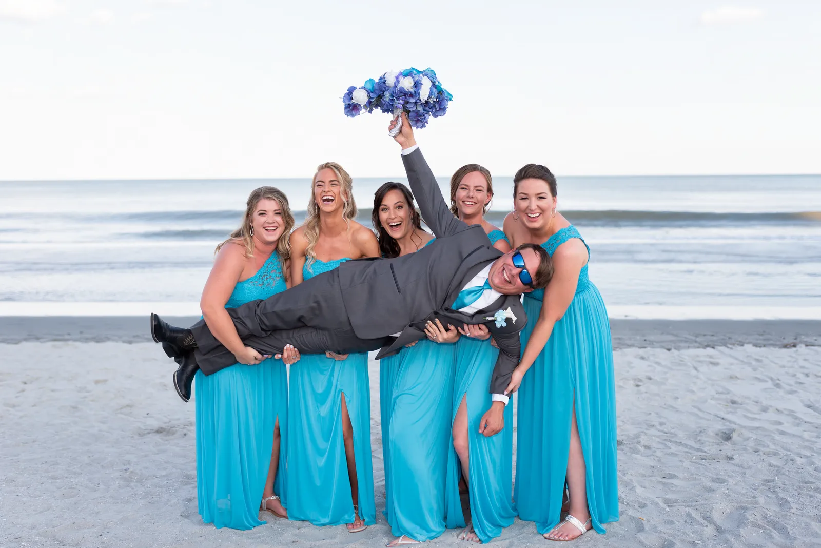 Fun picture with the bridesmaids holding up the groom by the ocean - Grande Dunes Ocean Club