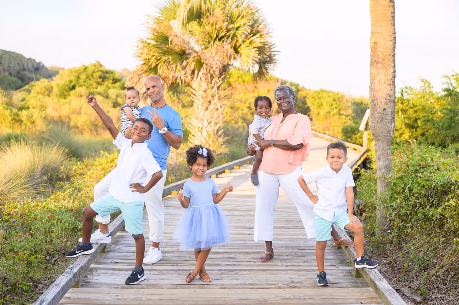Grandparents and grandkids striking silly poses on the wooden boardwalk under palmettos at Myrtle Beach State Park