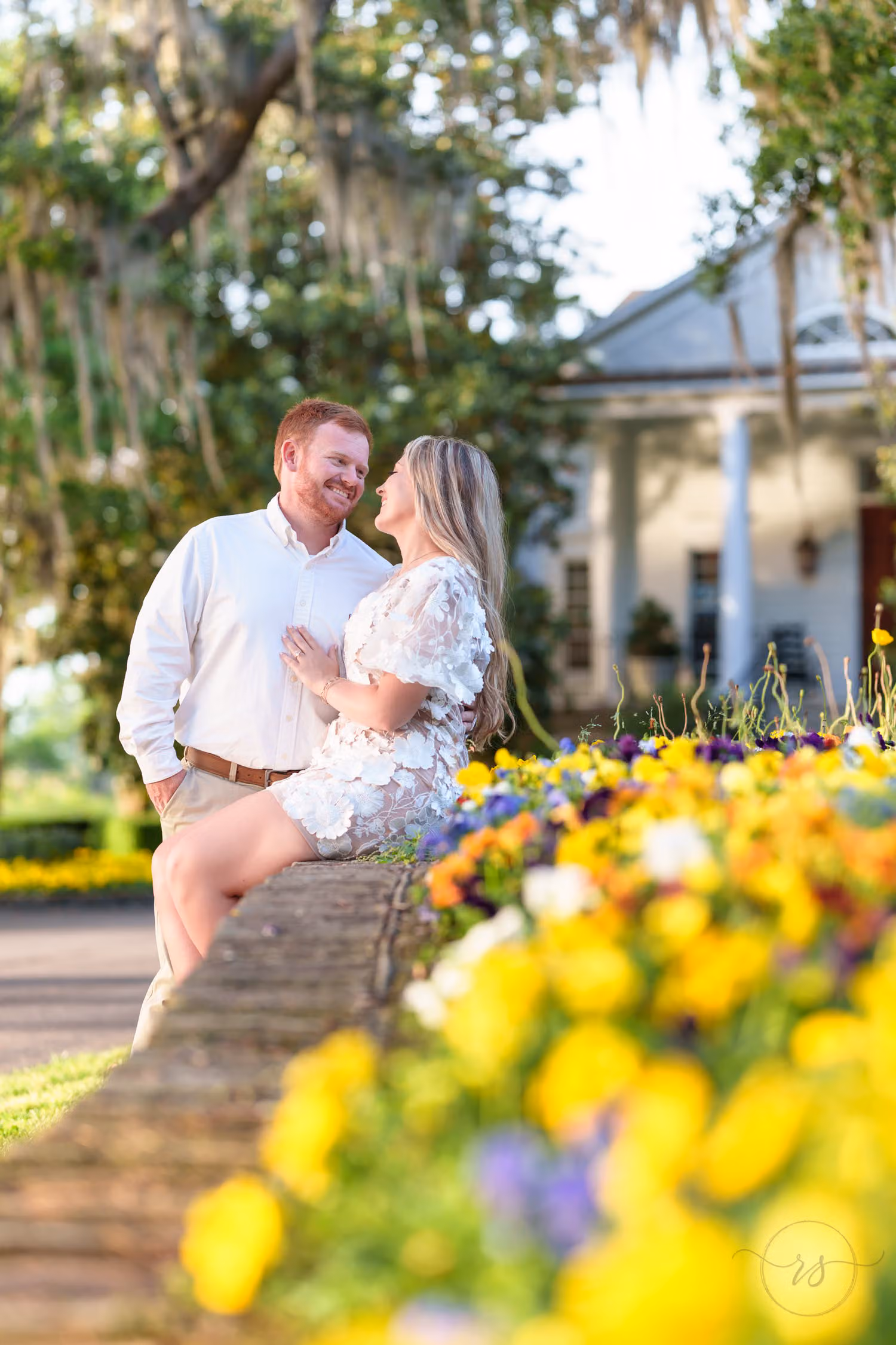 Couple smiling together beside a bed of yellow flowers near the clubhouse at Caledonia Golf & Fish Club