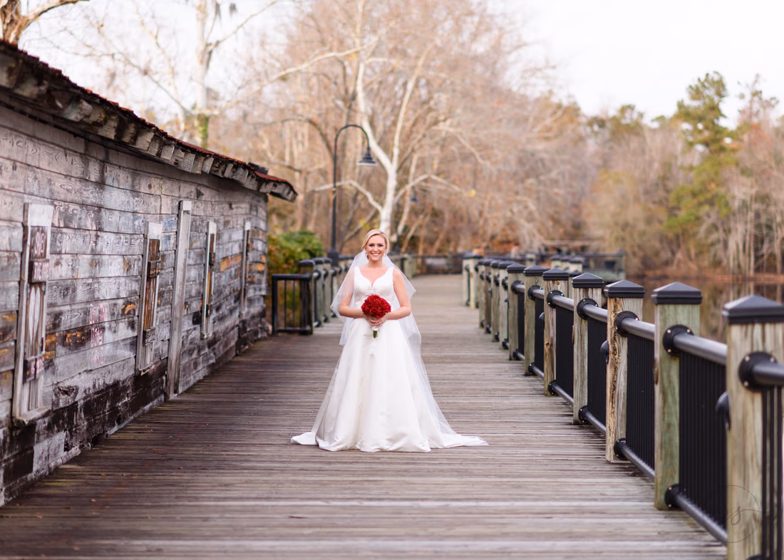 Wide view of the bride on the long boardwalk beside an old weathered building at the Conway River Walk