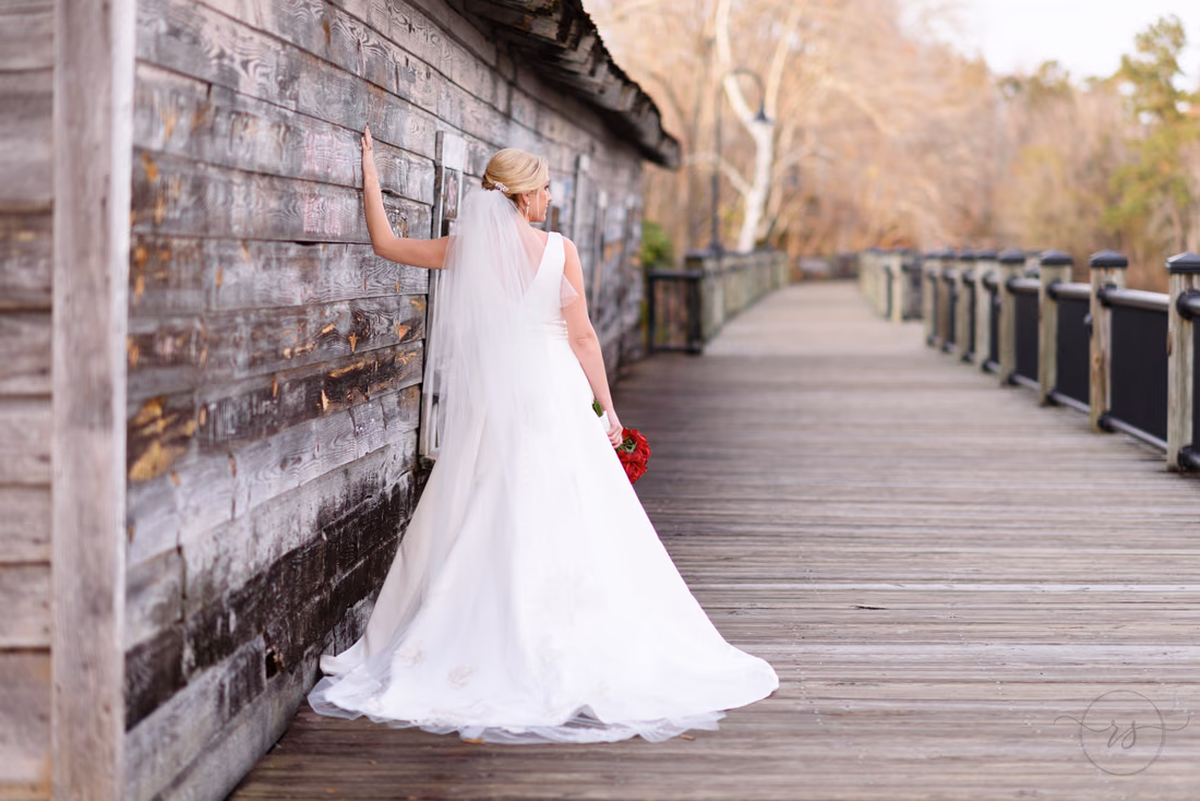 Bride resting her hand on the weathered wooden wall along the boardwalk at the Conway River Walk
