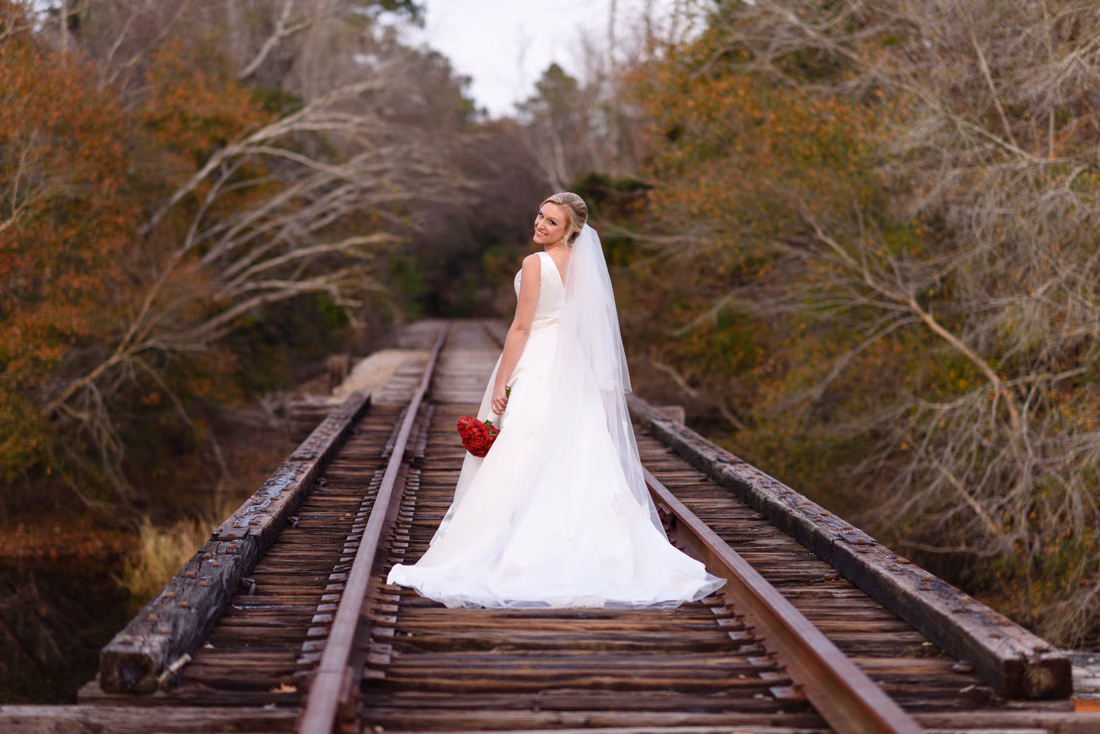 Bride looking back over her shoulder on the train tracks near the Conway River Walk