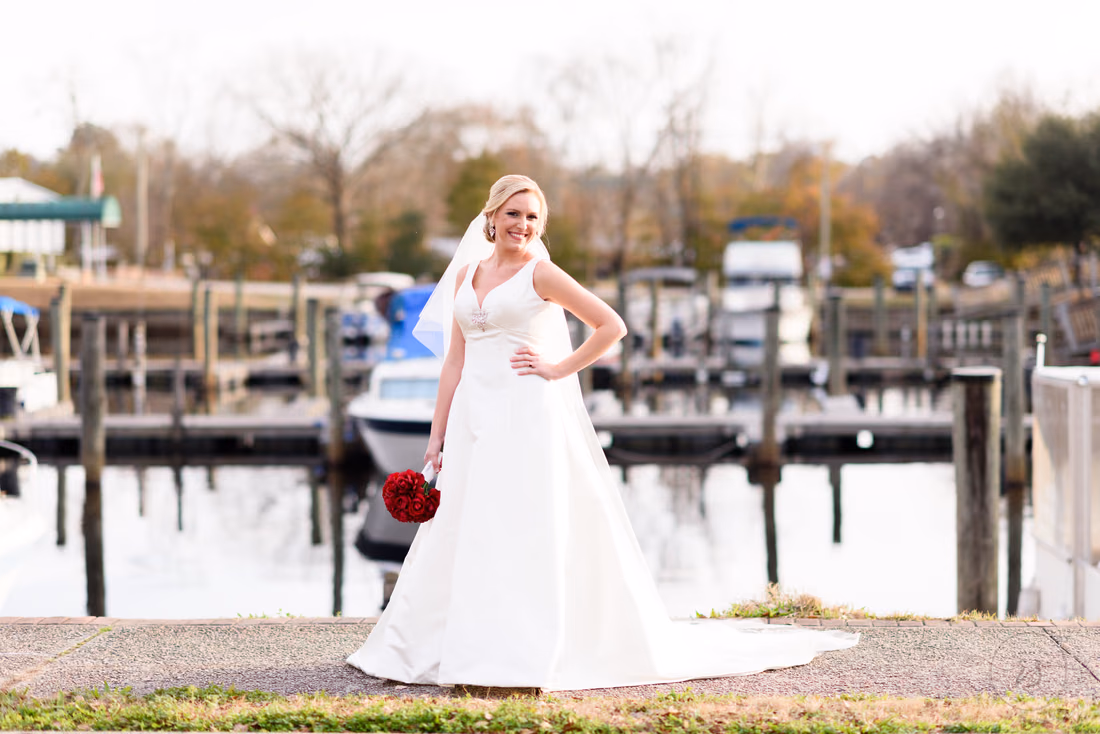 Bride with red roses standing in front of the marina docks at the Conway River Walk