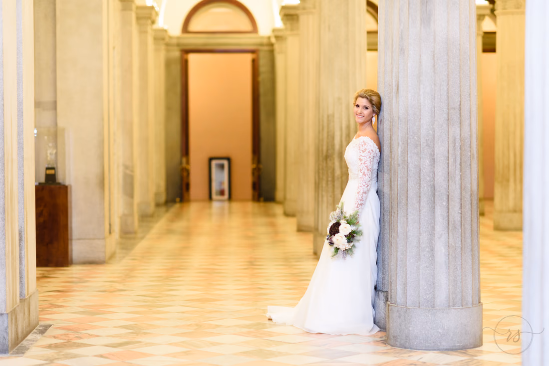 Bride leaning on a marble column in a long hallway with a patterned floor at the South Carolina State House