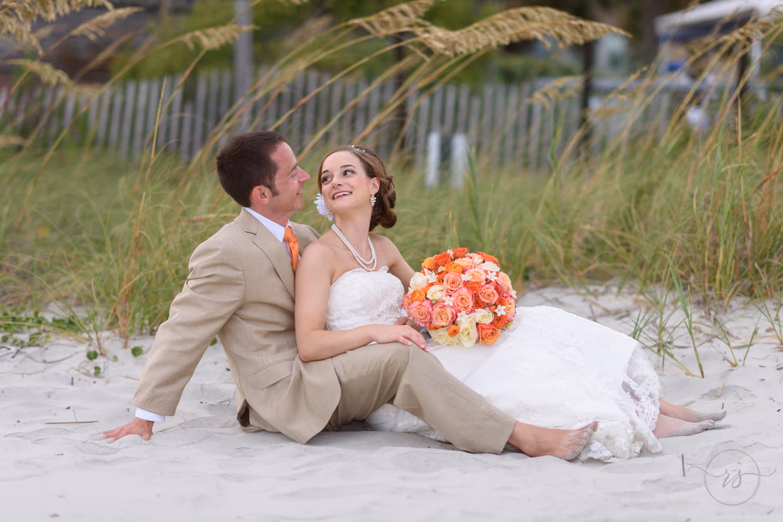 Bride sitting between the groom's legs smiling up at him - Hilton Myrtle Beach Resort at Kingston Resorts