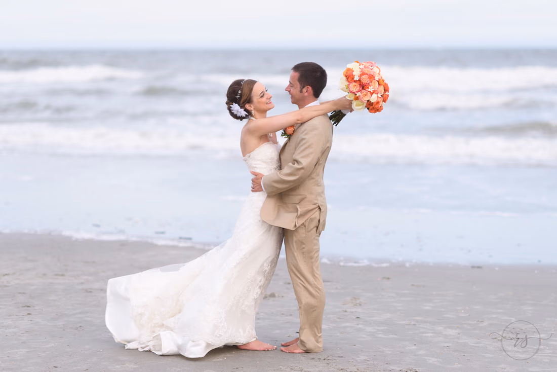 Bride with arms around groom holding flowers in the air - Hilton Myrtle Beach Resort at Kingston Resorts