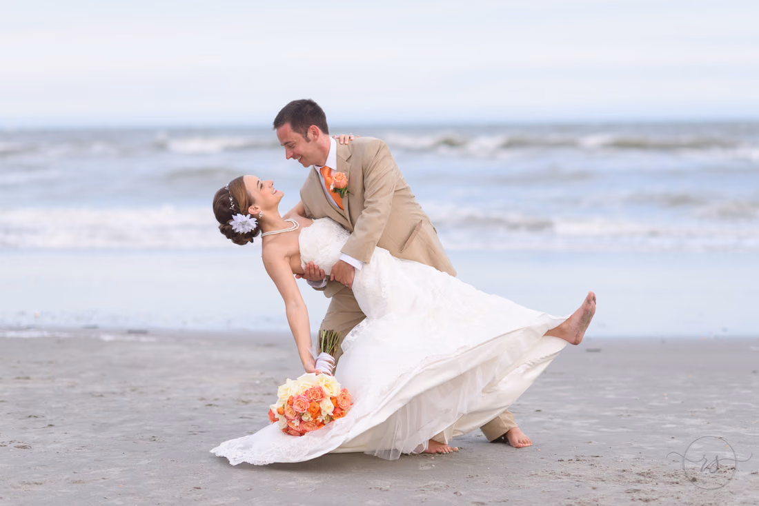Groom dipping back bride in front of the ocean - Hilton Myrtle Beach Resort at Kingston Resorts