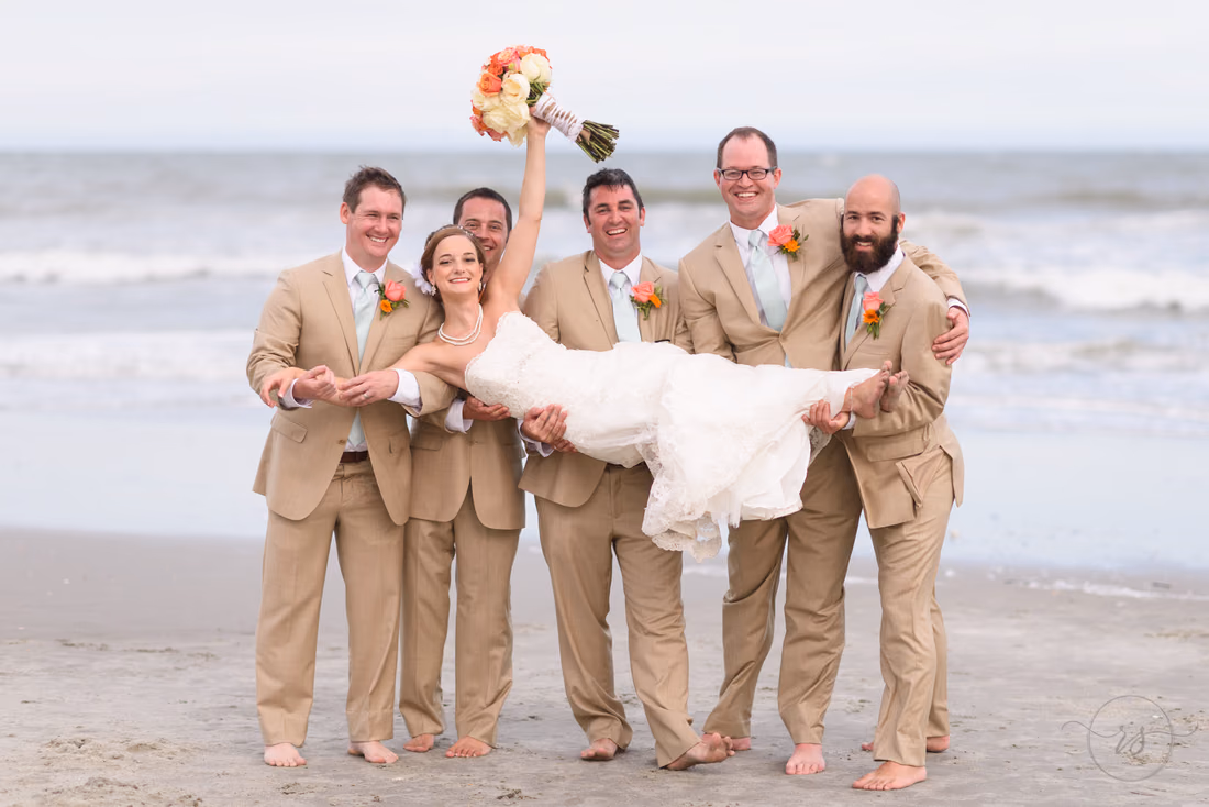 Groomsmen lifting up bride in front of ocean - Hilton Myrtle Beach Resort at Kingston Resorts