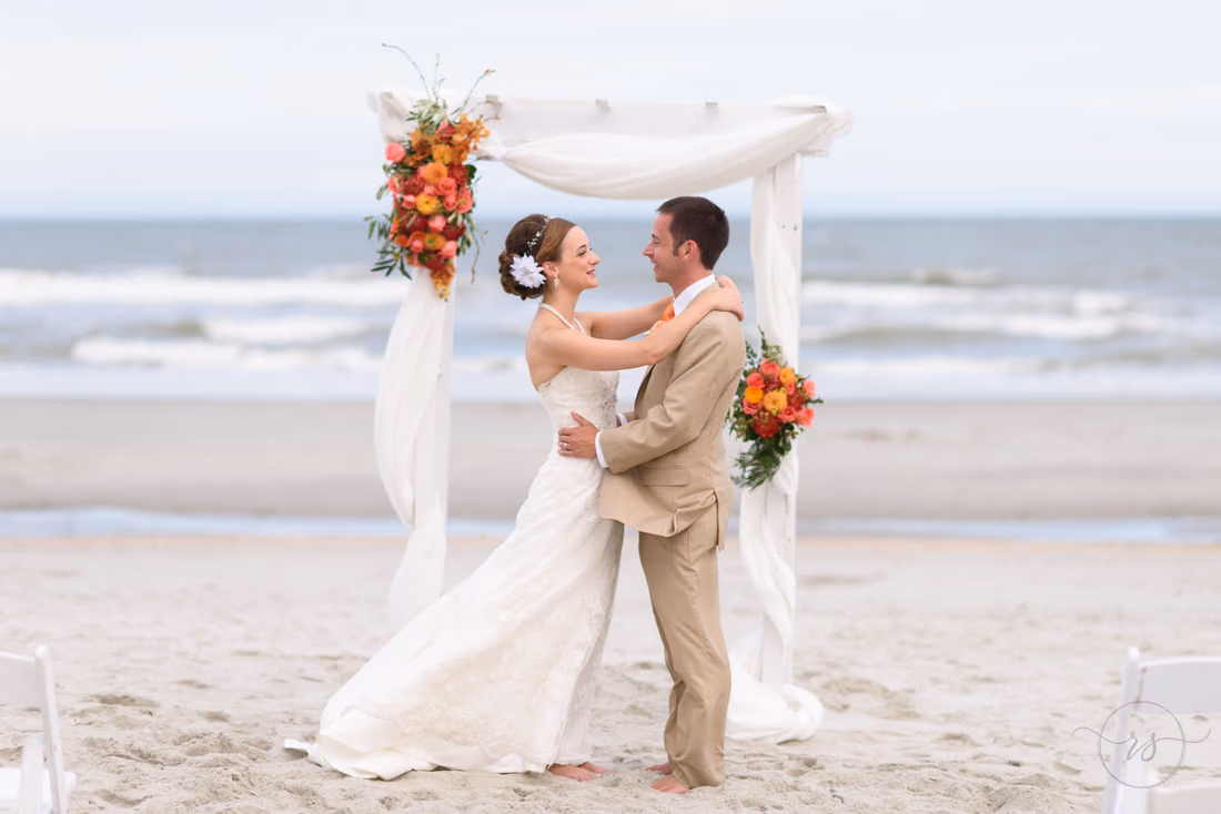 Happy couple in front of beach wedding arbor - Hilton Myrtle Beach Resort at Kingston Resorts