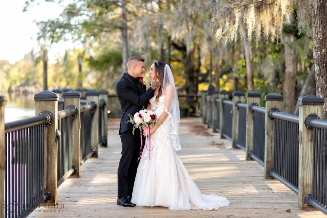 Bride and groom stand on the boardwalk under Spanish moss at the Conway Riverwalk