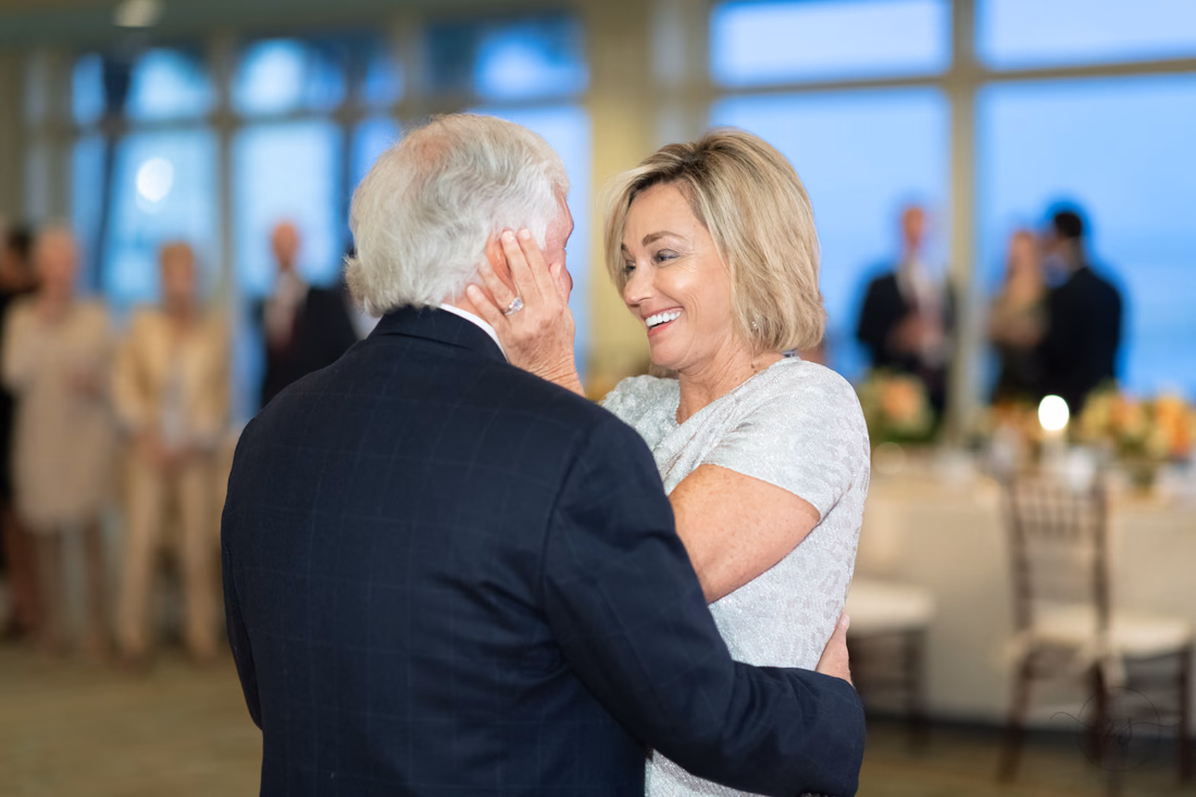 Groom touches the bride's face as she laughs during their first dance at the Dunes Golf and Beach Club in Myrtle Beach