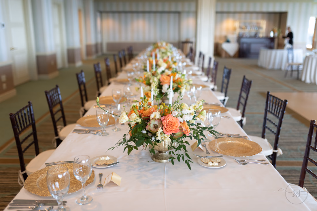Long reception table with peach and orange flower centerpieces at the Dunes Golf and Beach Club in Myrtle Beach