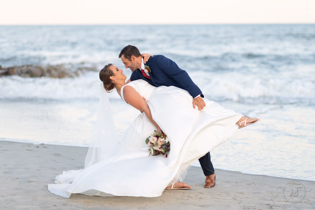 Groom dipping the bride as her dress swings out by the ocean - Pelican Inn - Pawleys Island