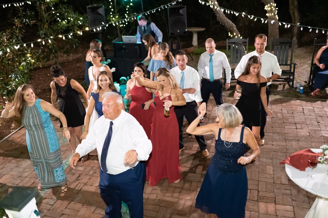 Guests line dancing on the brick dance floor under string lights - Pelican Inn - Pawleys Island