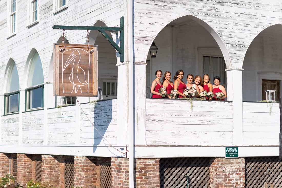 Bride and bridesmaids on the porch beside the Pelican Inn sign - Pelican Inn - Pawleys Island