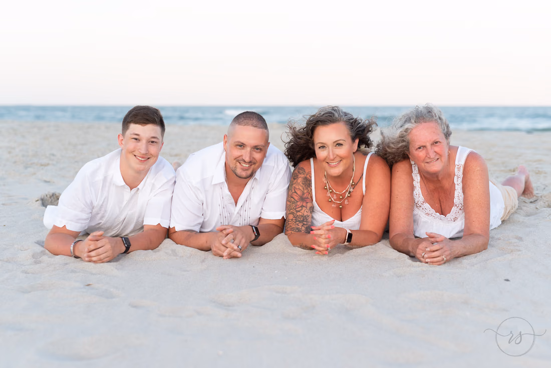 Family of four lying on their stomachs in the sand at Huntington Beach State Park