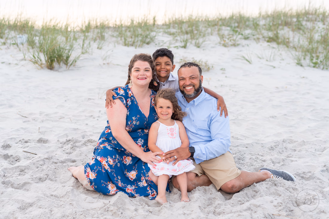 Family of four standing together by the dunes at Huntington Beach State Park