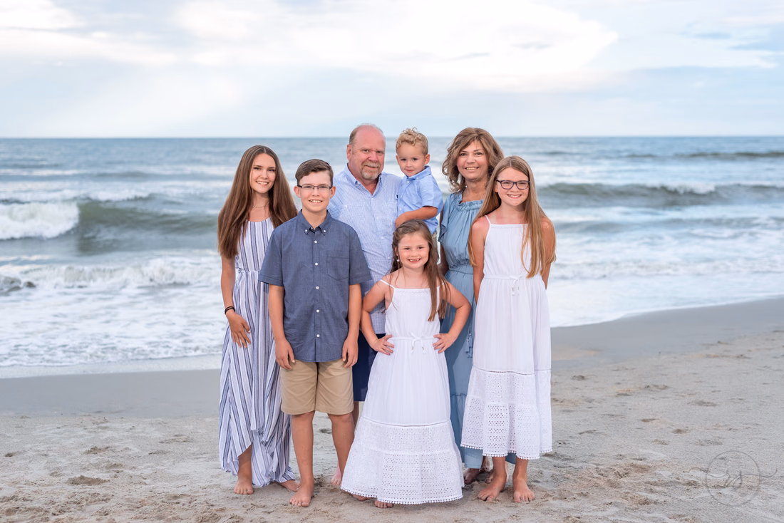 Family standing together at the water's edge at Huntington Beach State Park