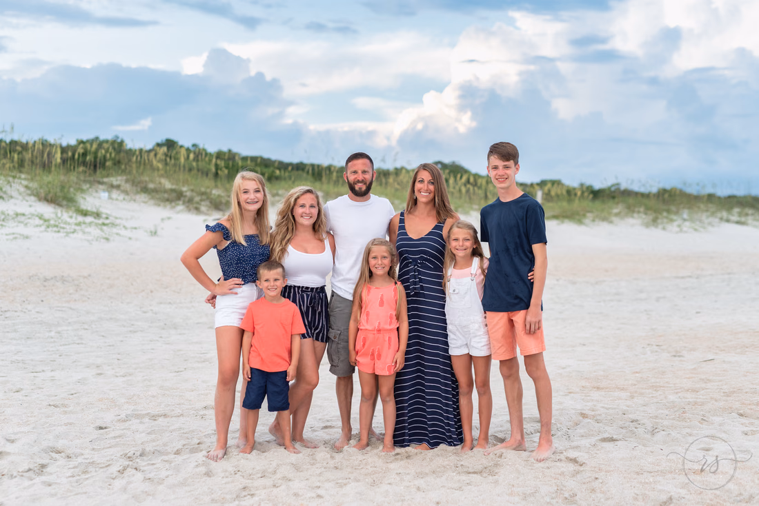 Family group in coral and navy standing by the dunes at Huntington Beach State Park