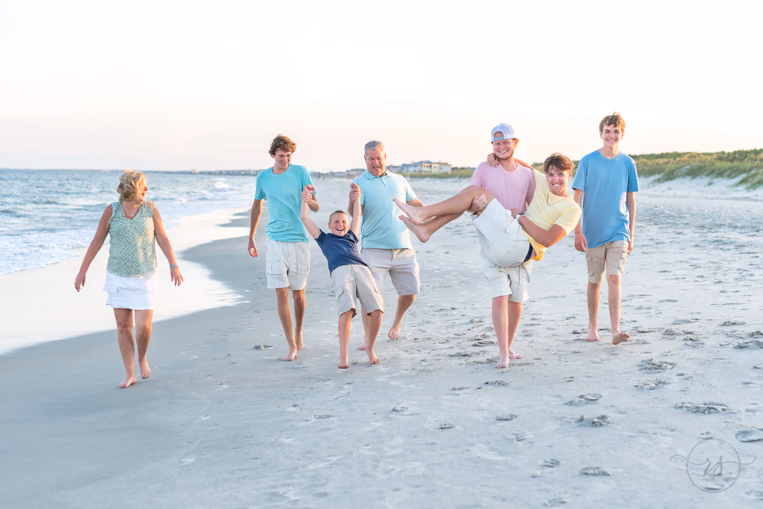 Family on the beach with one of the parents carrying a little boy at Huntington Beach State Park