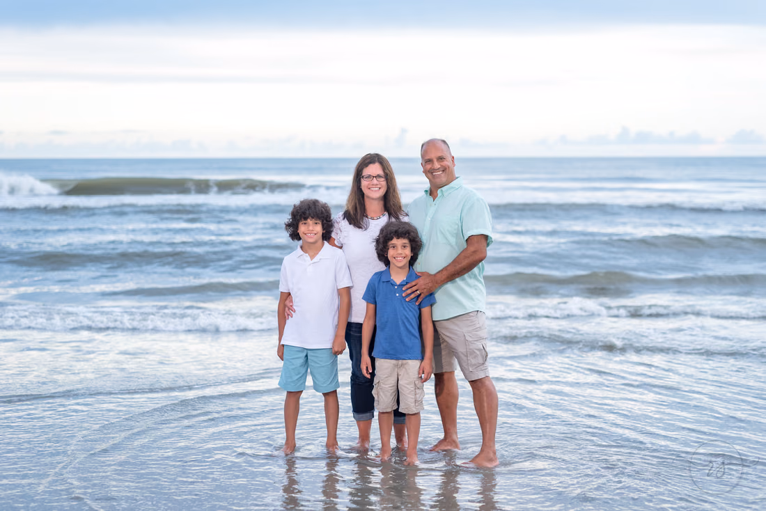 Family of four standing in the shallow surf at Huntington Beach State Park