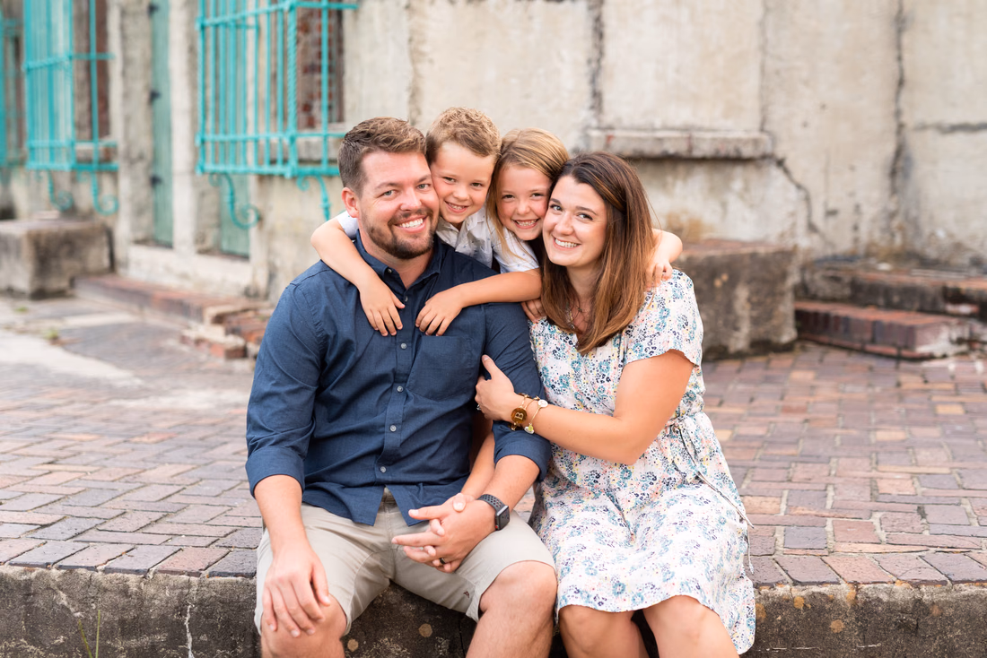 Two boys hug their parents from behind on the brick steps of Atalaya Castle at Huntington Beach State Park