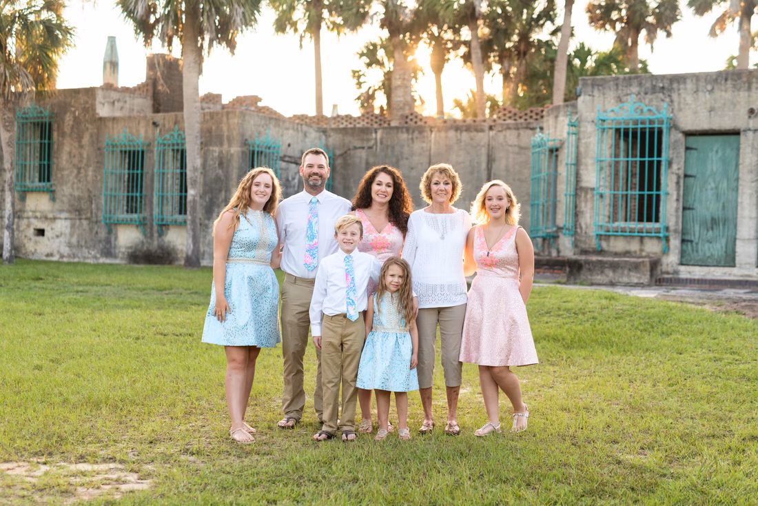 Family in pastel blue and pink standing on the lawn in front of Atalaya Castle at Huntington Beach State Park