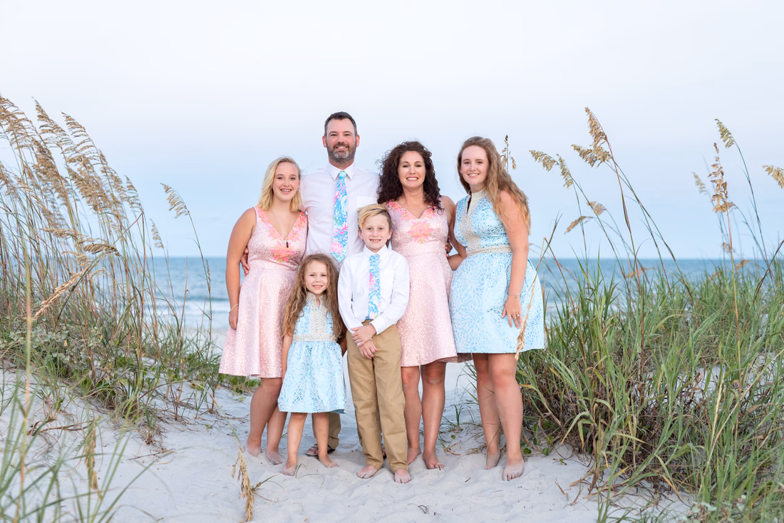 Family in pastel blue and pink standing by the sea oats at Huntington Beach State Park