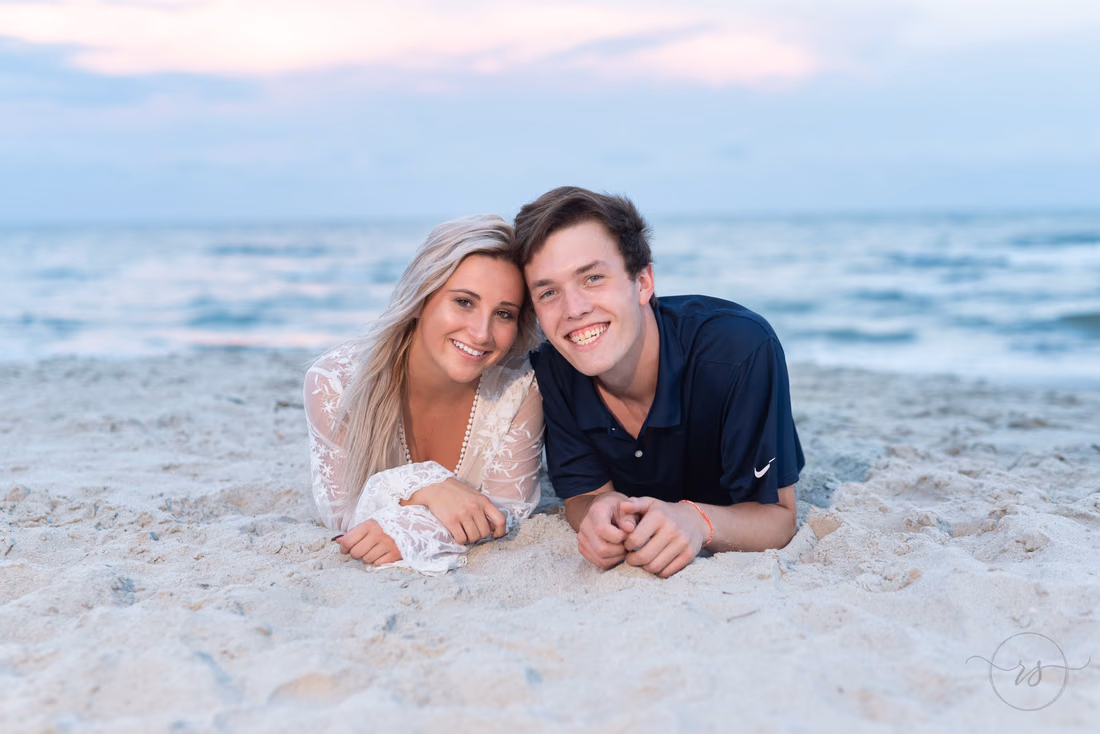Young man and young woman lying in the sand in front of the ocean at Huntington Beach State Park