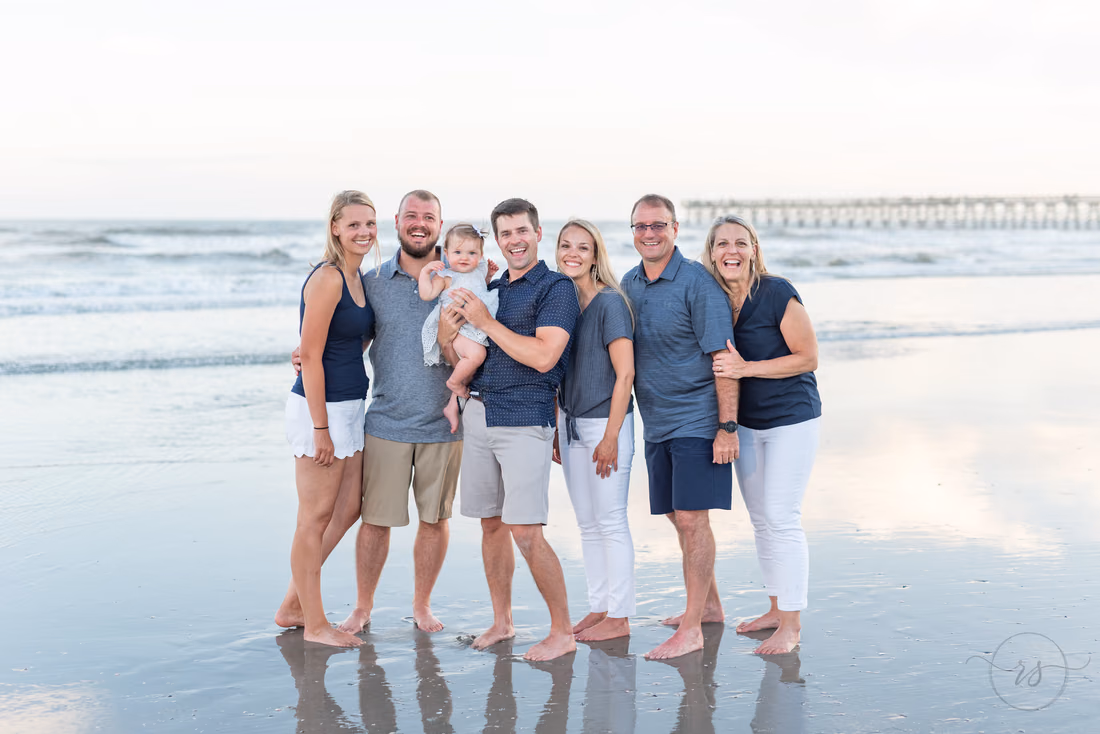 Family at the water's edge with the Cherry Grove Pier behind them in North Myrtle Beach